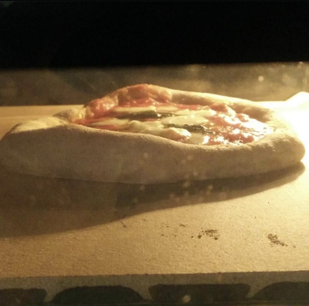Pizza cotta su pietra refrattaria in forno comune.